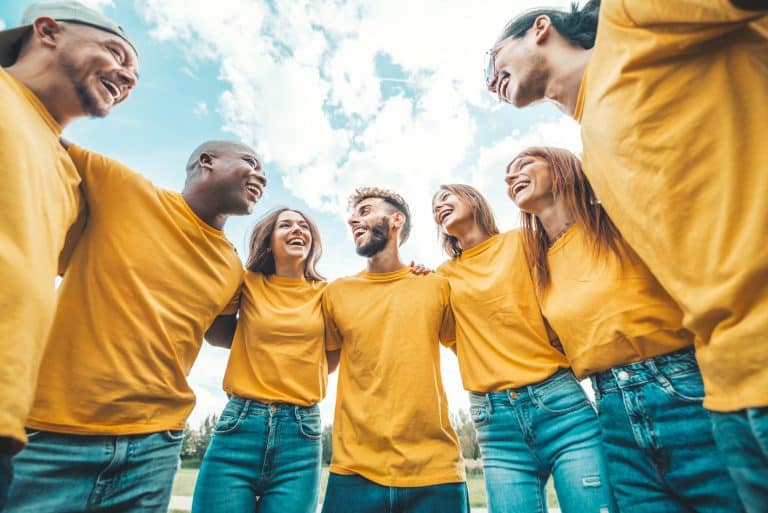 Group of people in yellow t-shirts with arms on each other's shoulders