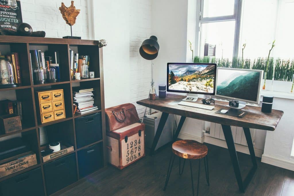 Home office space with two computers on desk and shelves to the left