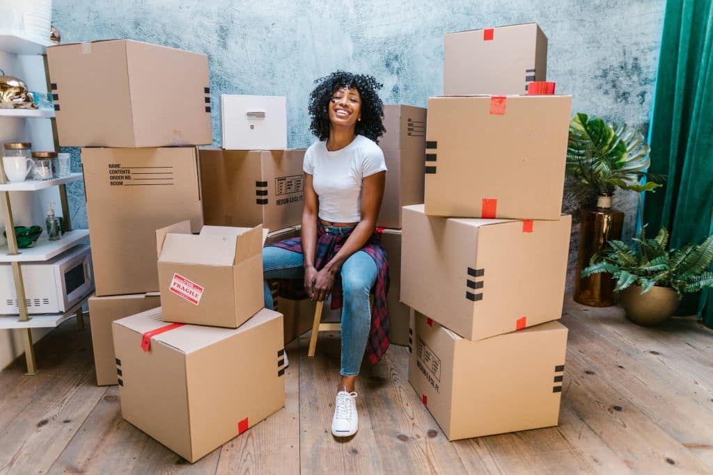 Woman sitting on a stool in a room surrounded by moving boxes