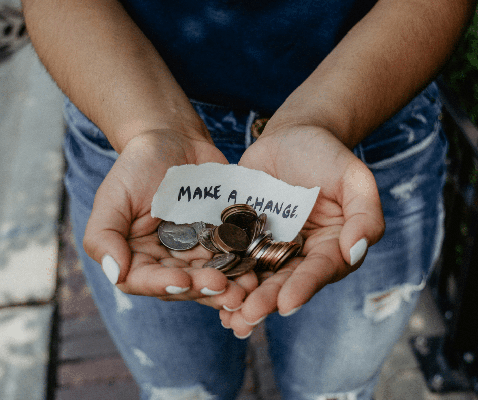 A woman holding coins in her hands with the words Make a change handwritten on a pice of paper.